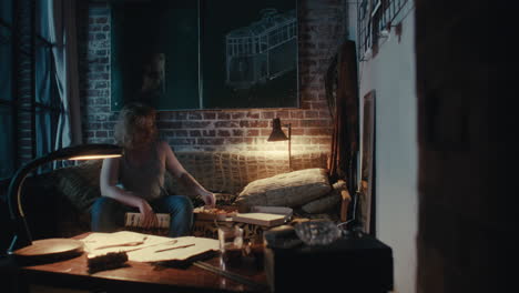 man eating pizza in a cozy apartment at night
