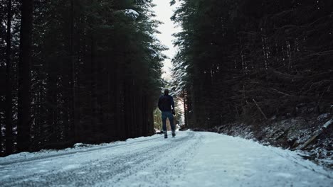 joven caminando por una carretera en un denso bosque de abetos, levantando los brazos en el aire de felicidad y emoción