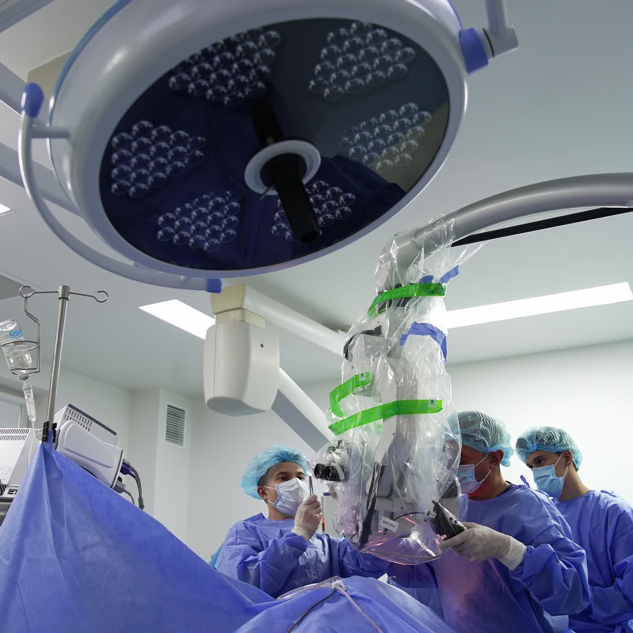 Team of doctors deal with advanced equipment during operation. Well-equipped surgery room from low angle perspective