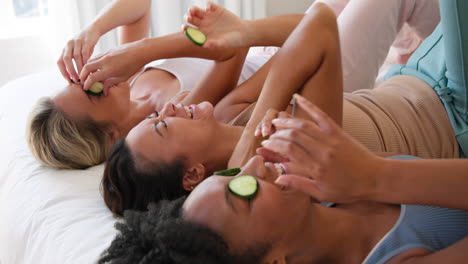 relaxing at home, diverse female friends enjoying cucumber eye masks on bed
