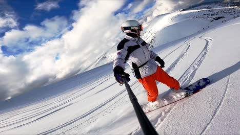 snowboarder taking selfie as he goes down the slope. man filming his descend and beautiful winter nature around.