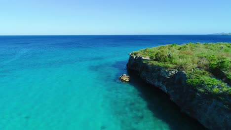 El-Dron-Desciende-A-Lo-Largo-De-La-Costa-Rocosa-Para-Aclarar-Las-Aguas-Azul-Turquesa-De-Curazao.