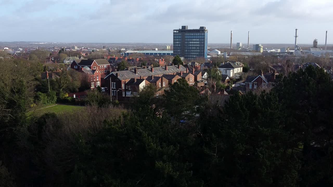 vista aérea sobre los árboles del parque a la ciudad industrial suburbio con rascacielos azules, merseyside, inglaterra