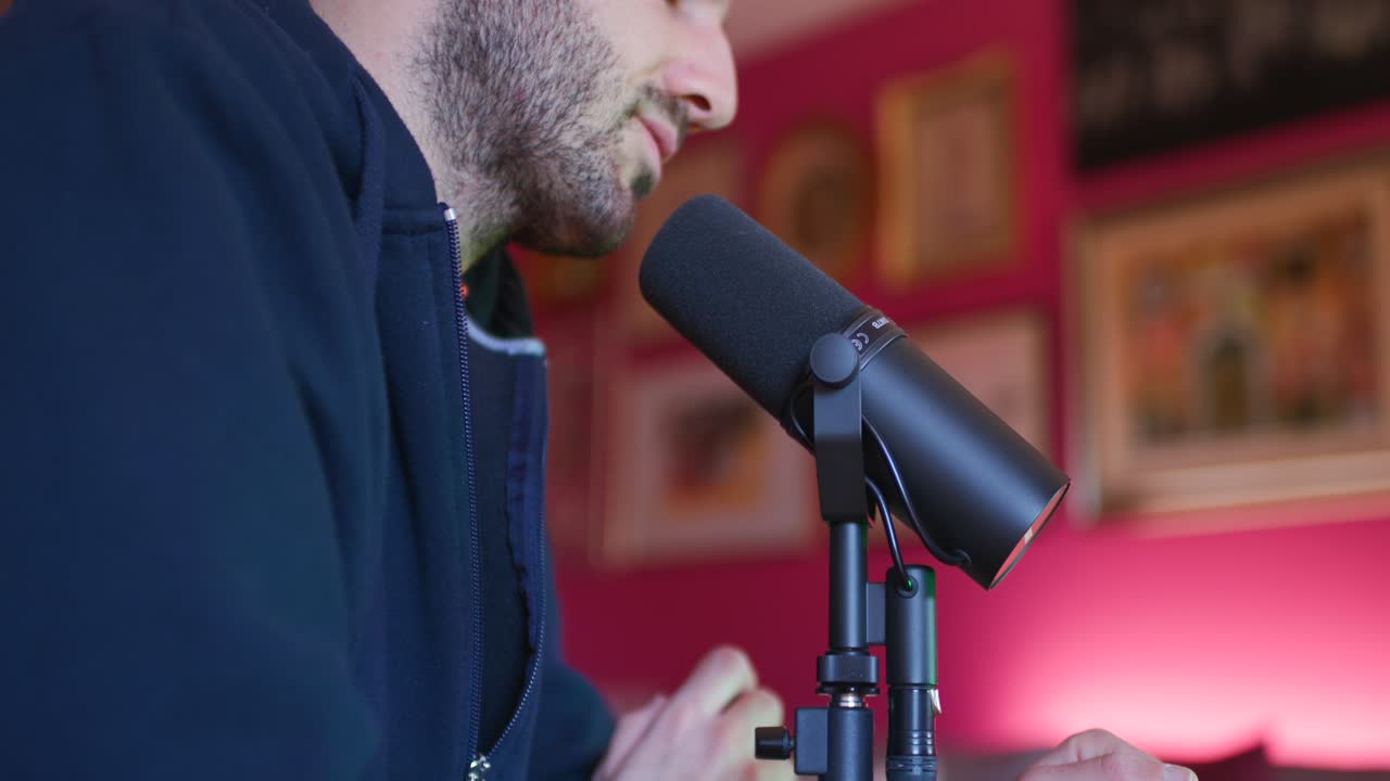 A man records a podcast by speaking into a microphone in a studio, sharing his thoughts and engaging with his audience