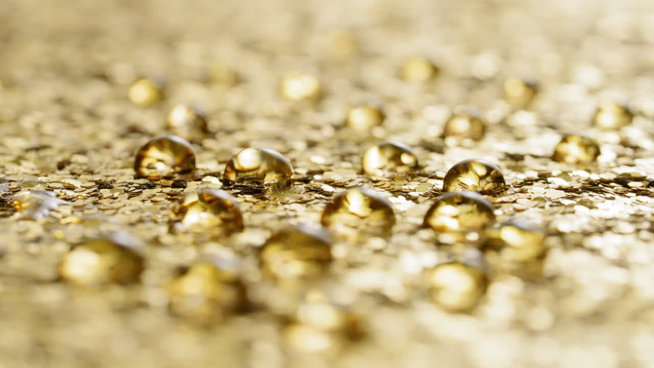 Rack focus across water droplets on gold sequins, abstract