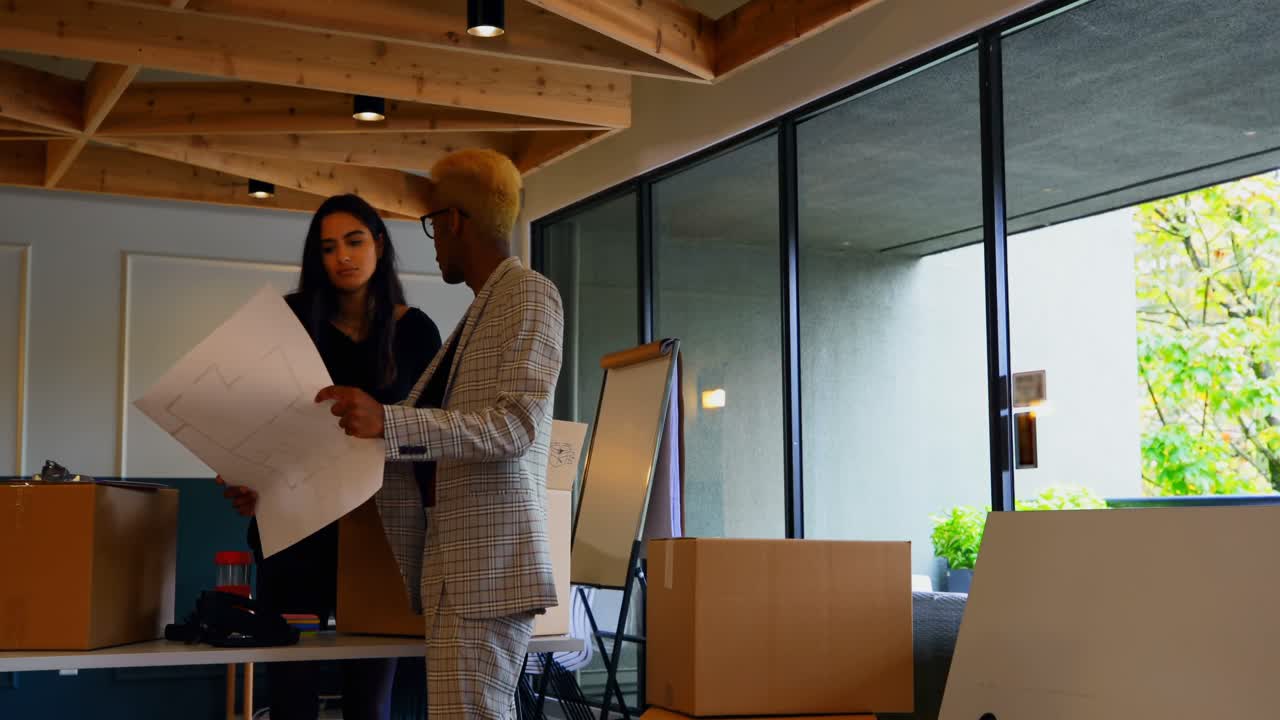Young mixed race business colleagues discussing over blueprint in modern office 4k