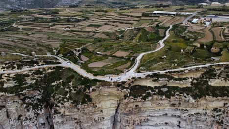 Pull-back-drone-shot-revealing-the-Maltese-countryside-sitting-atop-the-ragged-cliffs,-in-the-Mediterranean