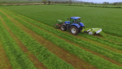 vista aérea de un tractor cortando la hierba en un gran campo verde