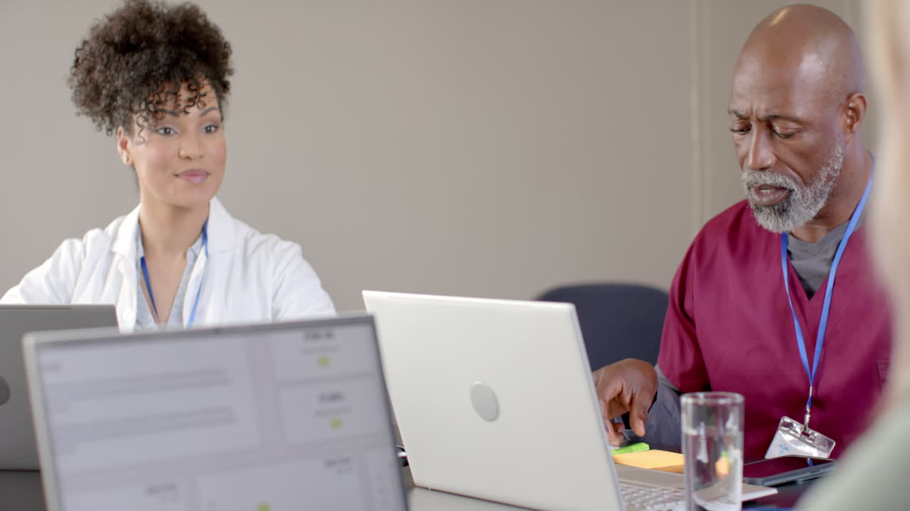diversos médicos usando computadoras portátiles en la sala de reuniones con espacio de copia, cámara lenta