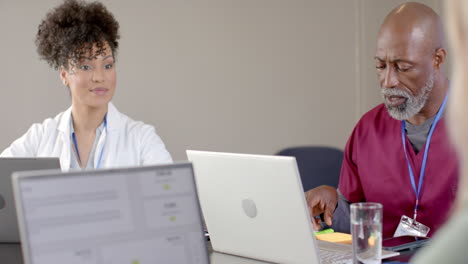 diverse doctors using laptops in meeting room with copy space, slow motion