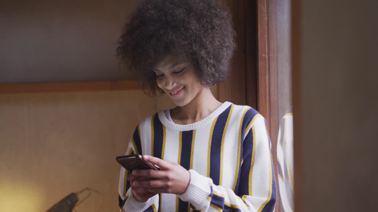 Mixed race woman texting at home