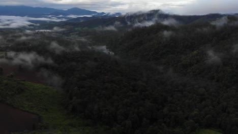 Drone-fly-over-the-remote-countryside-forest-hills-of-Pai,-Thailand-covered-in-rolling-hills-of-trees-and-very-low-thick-inversion-cloud-during-monsoon-season