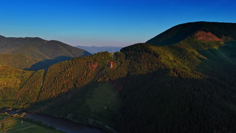 Scenic mountain cable car ride. A cable car glides above lush green mountains at sunset, providing stunning views of the valley below and distant peaks