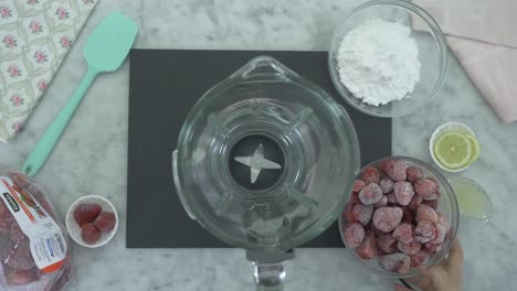 cerca de las manos de un chef poniendo frutas en una licuadora para hacer jugo