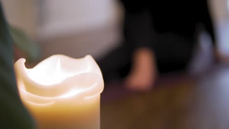 Yoga-concept:-white-candle-in-the-foreground-and-female-doing-yoga-in-the-background