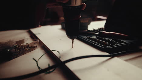 a slow motion of a carpenter drilling wood with a drill on the hard surface