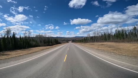 pov - driving on alaska highway through stone mountain provincial park of british columbia in northern canadian rocky mountains; concepts of road less traveled and not all who wander are lost
