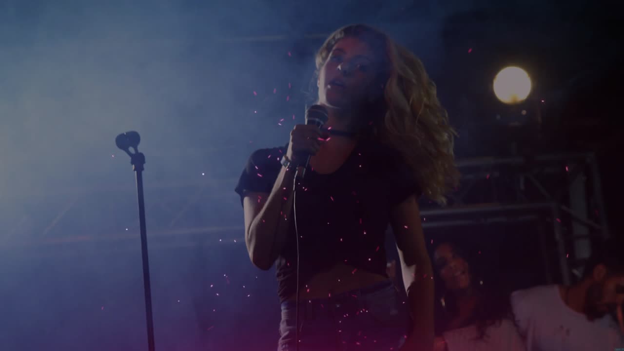 Music artist reacting to uptempo riff hairflipping and singing energizing crowd under pink lighting