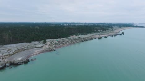 establishing aerial view of abandoned seaside fortification buildings at karosta northern forts on the beach of baltic sea , overcast day, wide drone shot moving forward