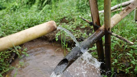 un dispositivo inteligente construido con bambú que se vuelca cuando el agua se llena en la tubería y la deja caer en el estanque debajo