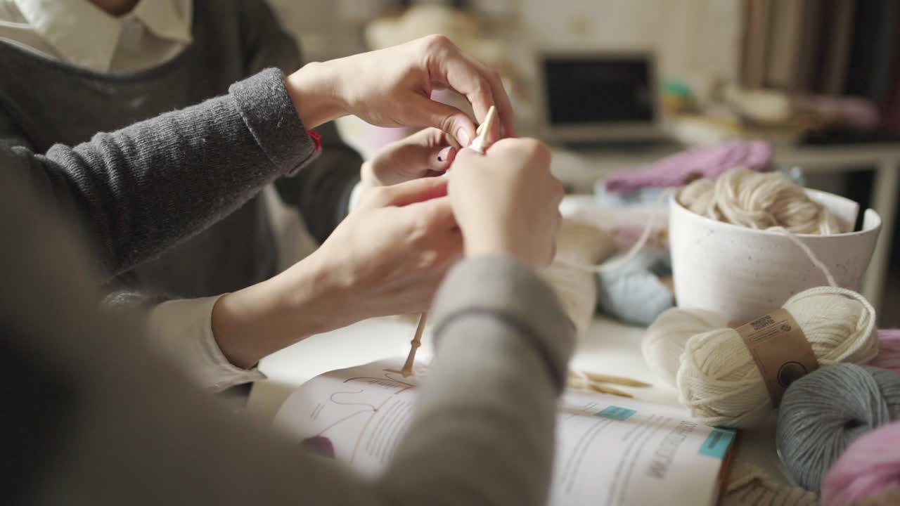 Mother learning daughter knitting needles yarn in home Woman hands knitting