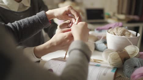 mother learning daughter knitting needles yarn in home woman hands knitting