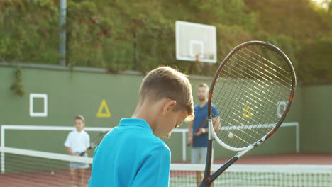 Rückansicht-Eines-Teenagers,-Der-Im-Sommer-Mit-Vater-Und-Kleiner-Schwester-Auf-Einem-Außenplatz-Tennis-Spielt