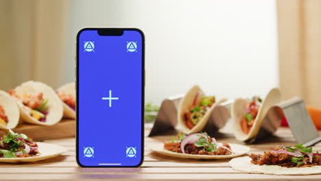 Tacos on a Table with a Smartphone Taking a Picture