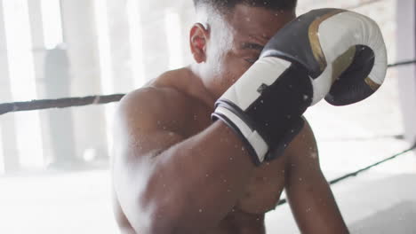 Animation-of-white-particles-falling-over-african-american-male-boxer-resting-after-training