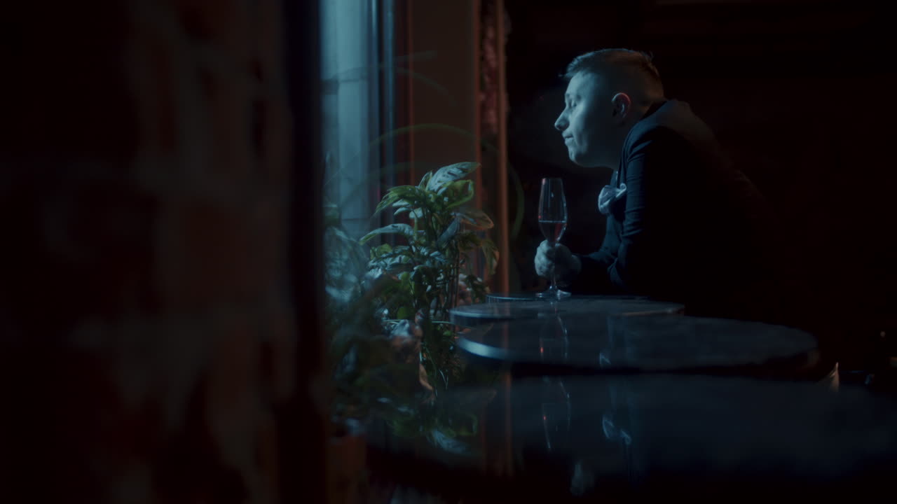 Man drinking wine by the window at night