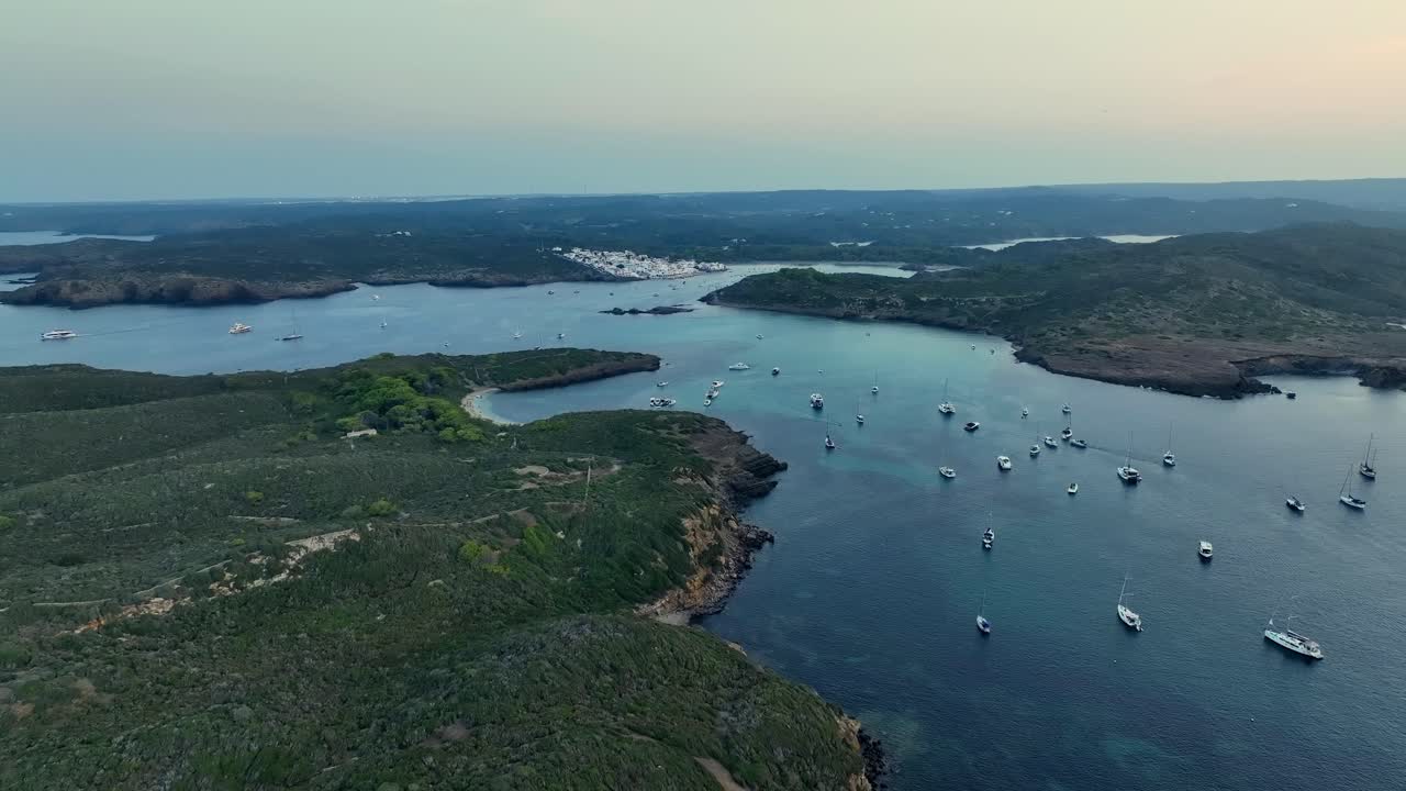 Drone shot of all the beautiful little sailboats anchored in the nature on Menorca, the amazing Spanish island in the mediterranean sea.