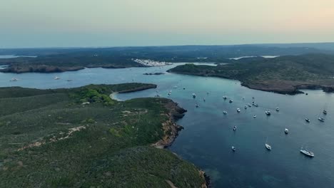 drone shot of all the beautiful little sailboats anchored in the nature on menorca, the amazing spanish island in the mediterranean sea.