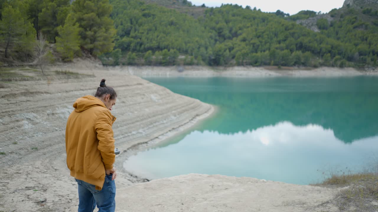 Man taking pictures by a turquoise lake