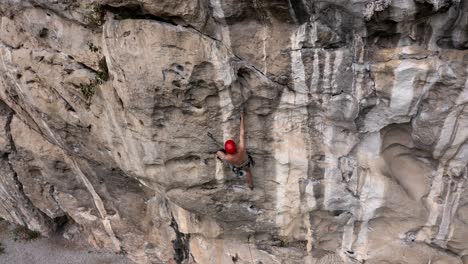 male rock climber climbing steep rock face in getu valley, china, aerial view