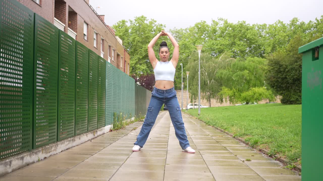 Woman dancing on a sidewalk in an urban park