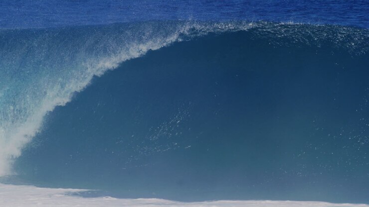 Medium view of textured strong powerful ocean water rising into wave with mist flying off top