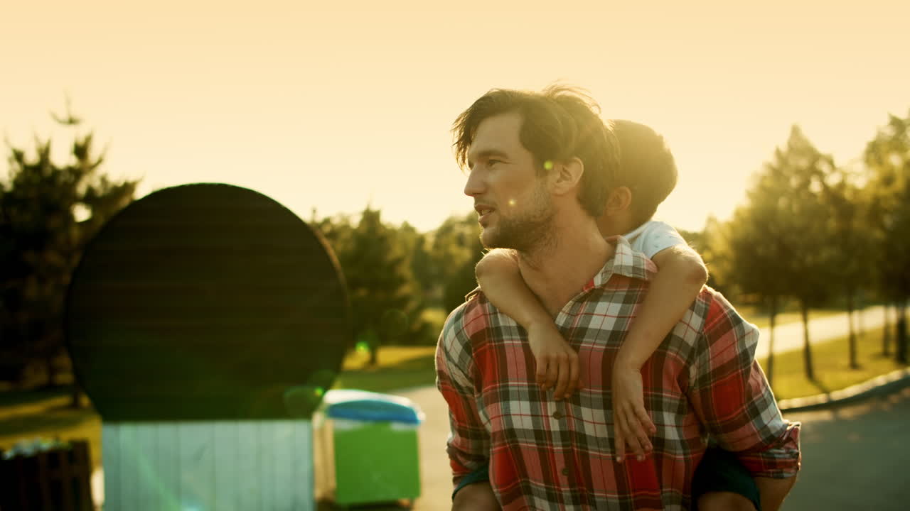 남자 가 소년 과 함께 거리 를  ⁇ 고 있다. 웃는 아버지 가 밖 에서 아들 을 안고 있다