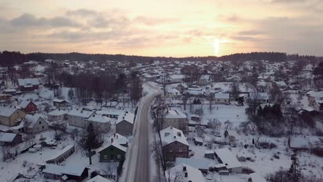 Drone-View-on-Snow-Covered-Houses-at-Sunset-Colors-in-Skies,-City-in-Winter