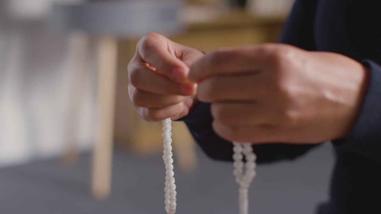 히잡을 쓰고 집에서 염주를 들고 기도하는 이슬람 여성의 클로즈업 1