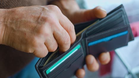 close up view of an old man's hands adding dollar bills to his wallet.