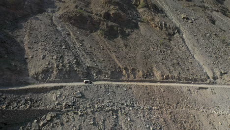 Drone-shot-of-vehicle-on-Fairy-Meadows-Road-in-Pakistan,-second-deadliest-highway-in-the-world,-revealing-aerial-shot