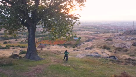 Mädchen-Mit-Einem-Fahrrad,-Das-Unter-Einem-Großen-Baum-Ruht-Und-Den-Wunderschönen-Sonnenuntergang-Genießt