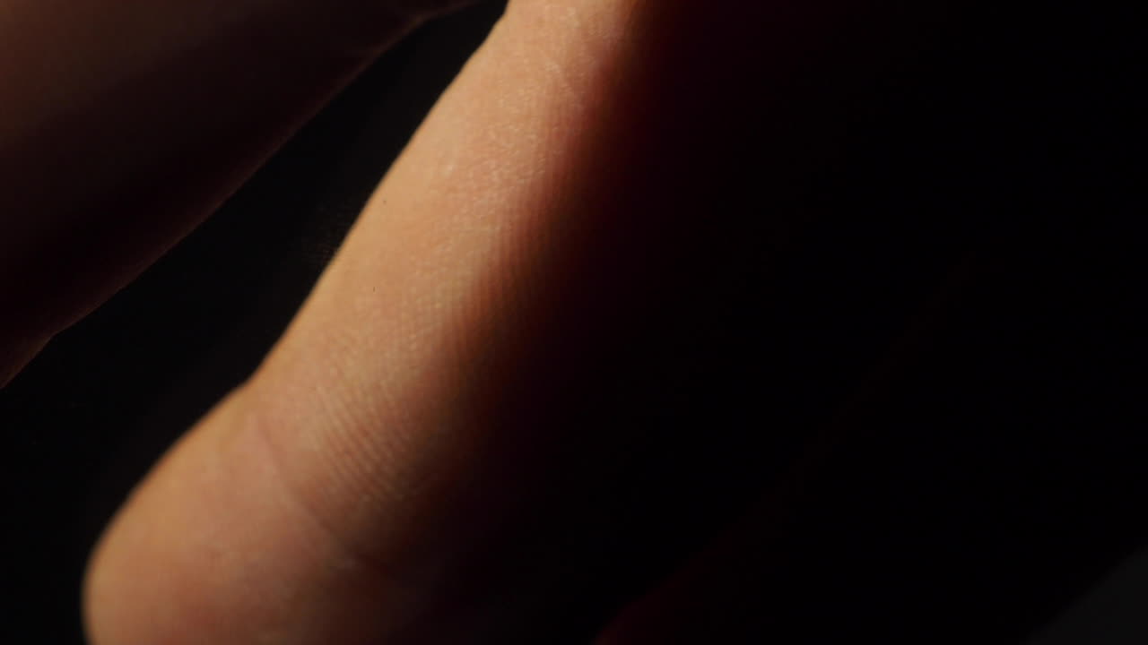 Fingers stroking in simple black background sensual closeup shot