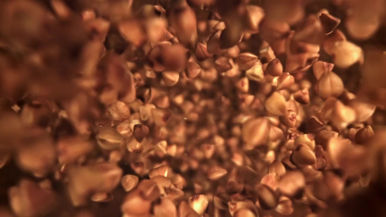 Grani di grano saraceno che cadono e vorticano in slow motion