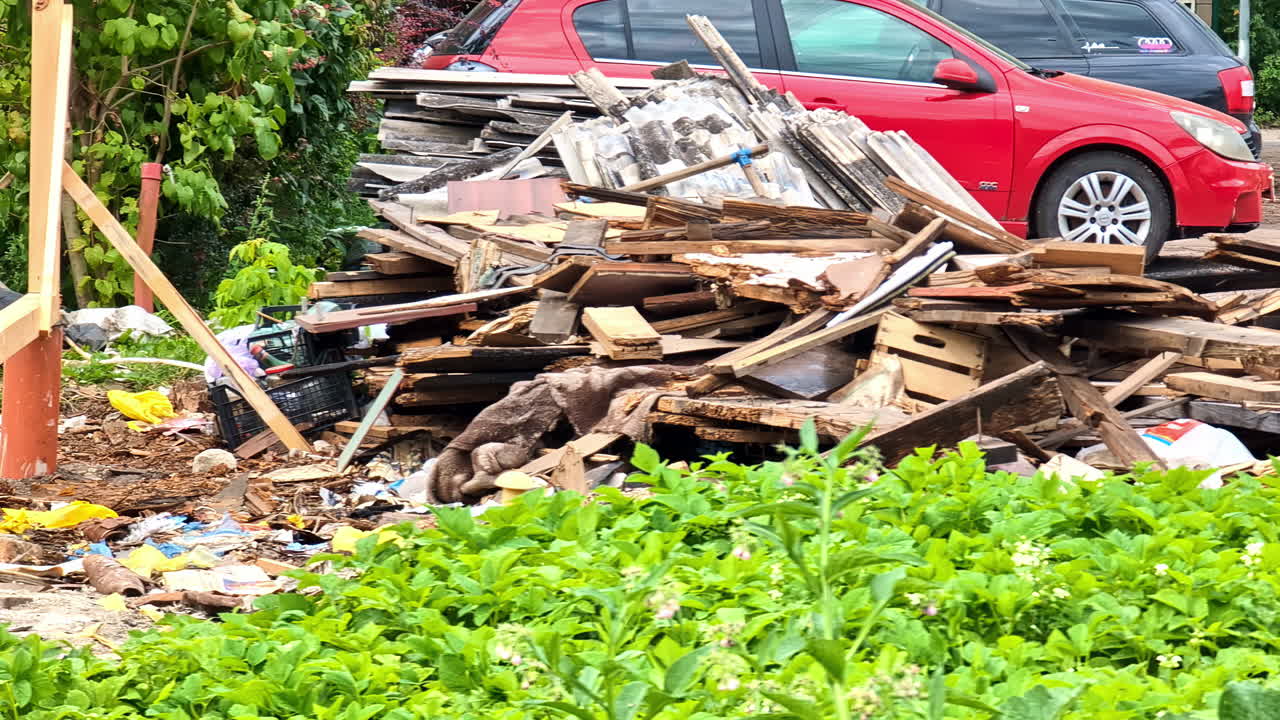 Scattered wooden remains from a collapsed house on the side of street