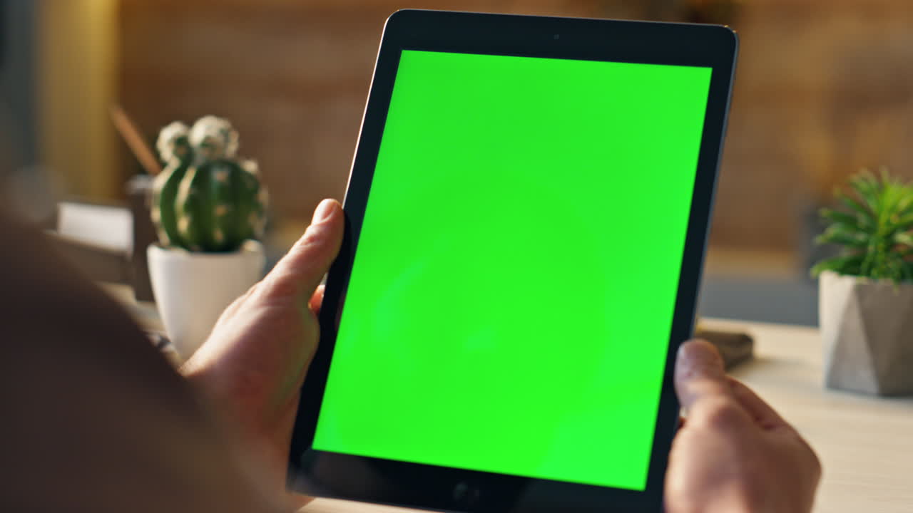 un trabajador independiente desconocido mirando una tableta de pantalla verde en el escritorio de cerca. hombre sosteniendo una pestaña