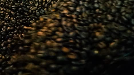 granos de café oscuro recién tostados mezclados y rotados por una máquina profesional con detalles de cierre