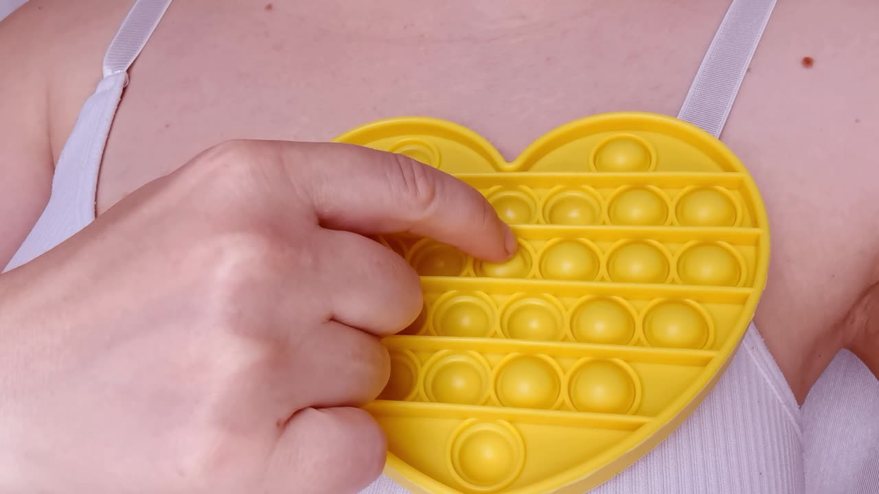 새로운 아기 장난감. 손가락 놀이. 재미있는 색. 성인 손 압축 둥근 실리콘. 형태 변경. 노란색 심장 모양