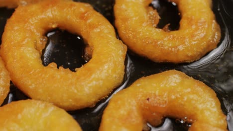 fried crispy onion rings in a frying pan with boiling oil top view. roasted onion rings for snacks at bar, cafe. fast food. delivery. beer snacks