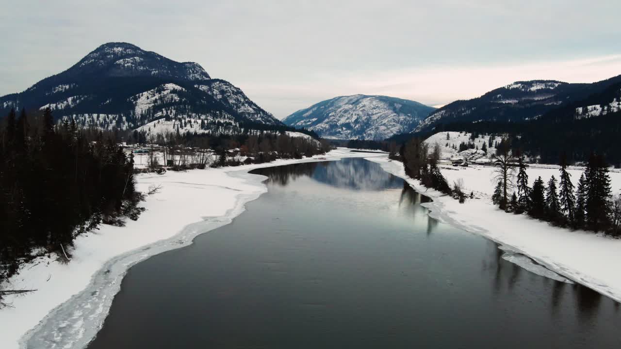 Ilmakuva osittain jäätyneestä North Thompson -joesta, jossa heijastuvat lumipeitteiset vuoret Little Fortissa, Brittiläisessä Kolumbiassa.